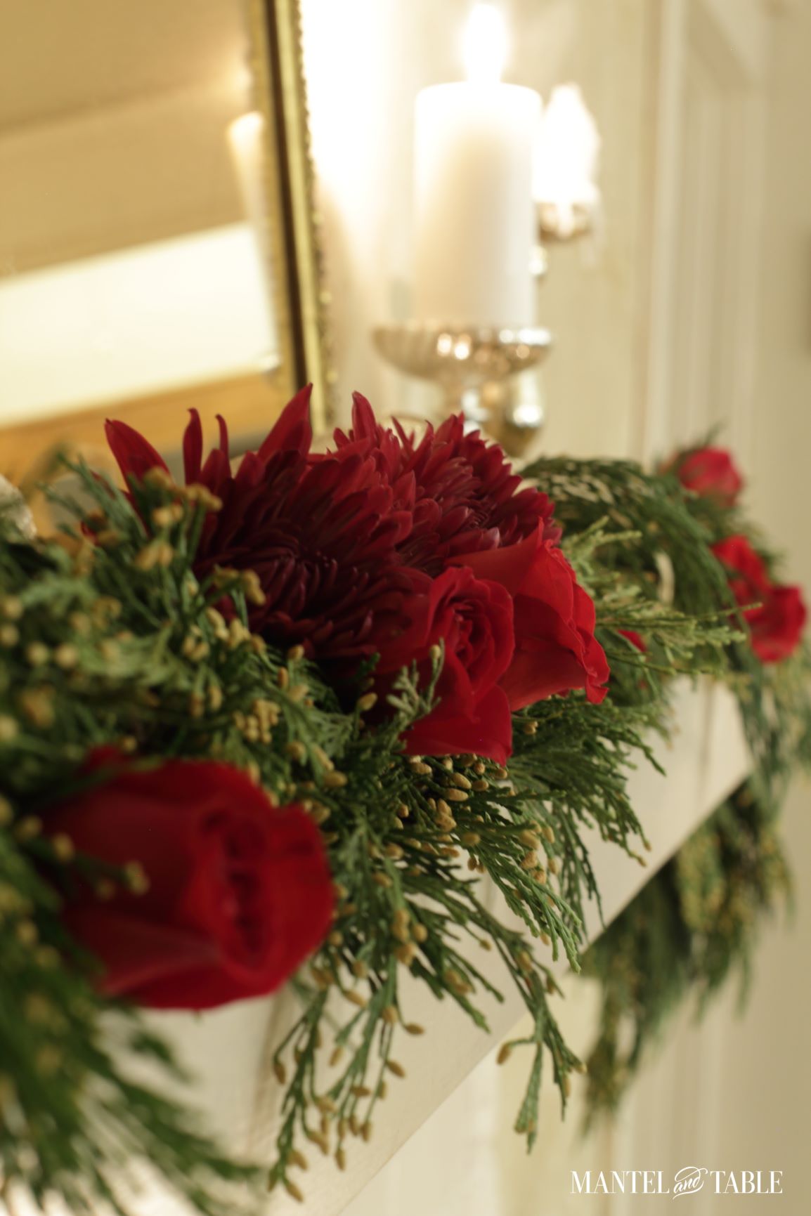 Evergreen garland, red roses, and red mums on mantel