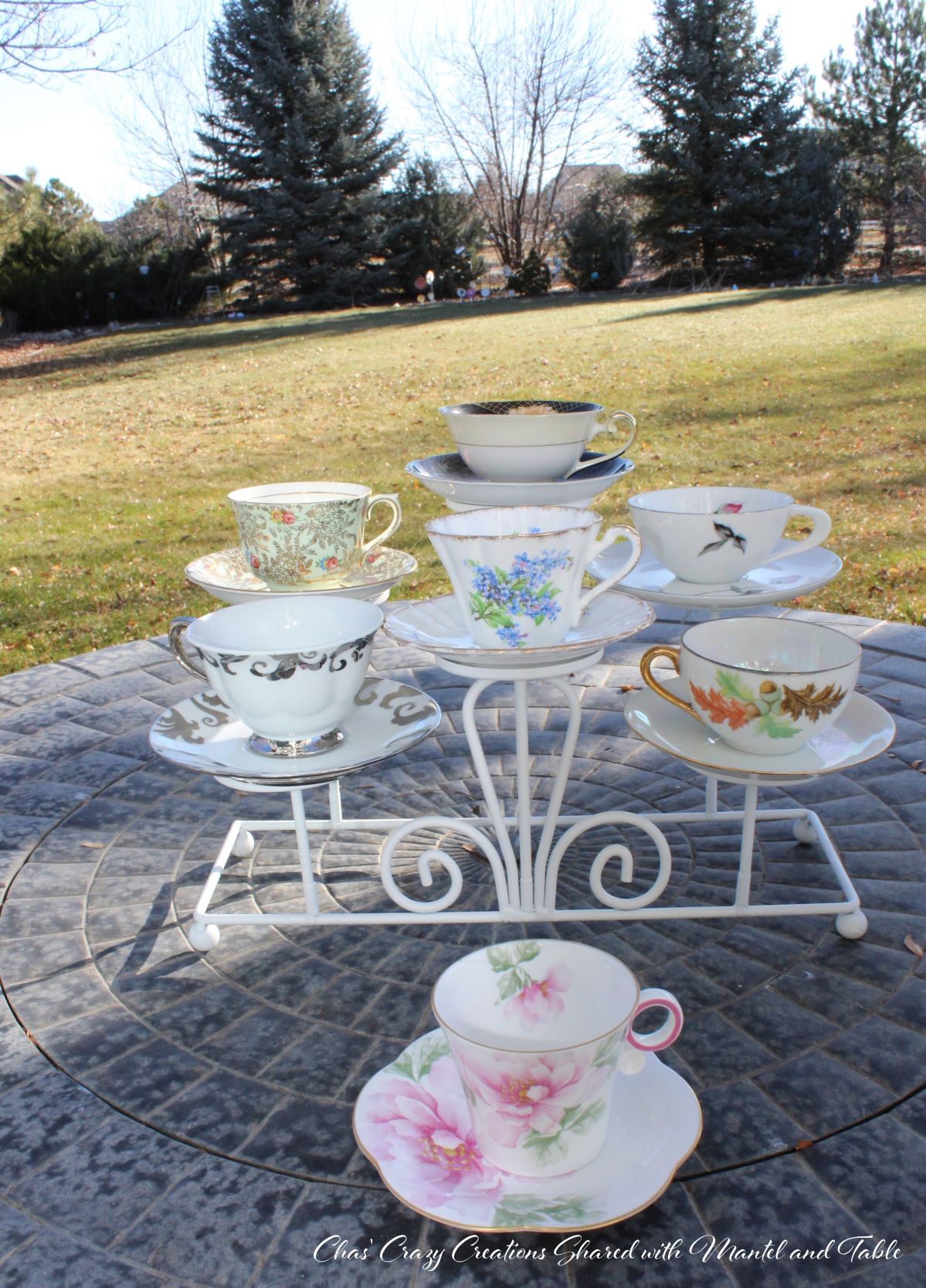 Teacup adventure - pink flowered teacup on patio with 6 other teacups on stand