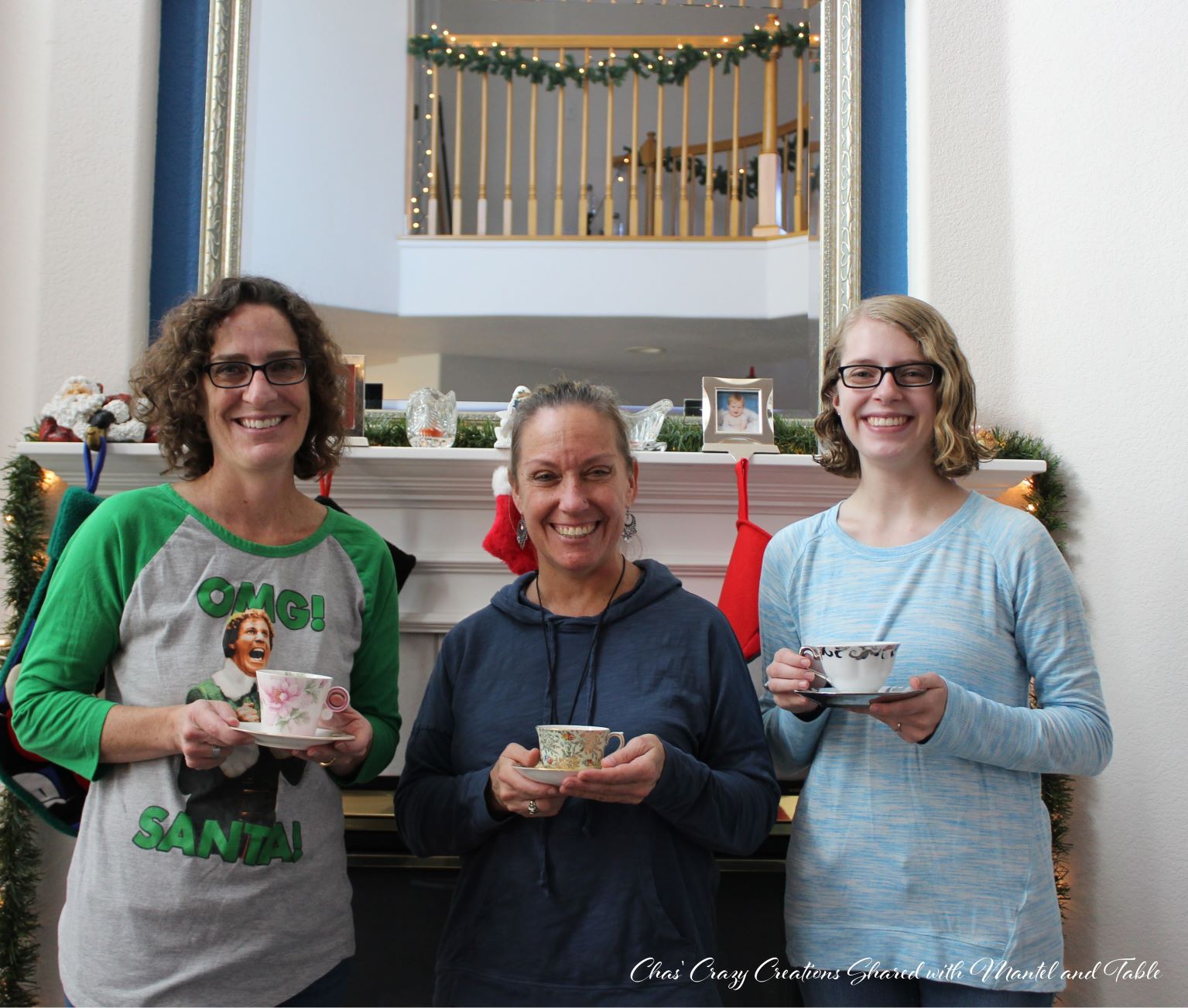 Three women holding teacups, standing in front of Christmas fireplace