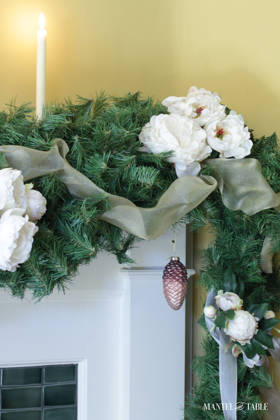 Closeup of blush pinecone ornament in white peony mantel garland