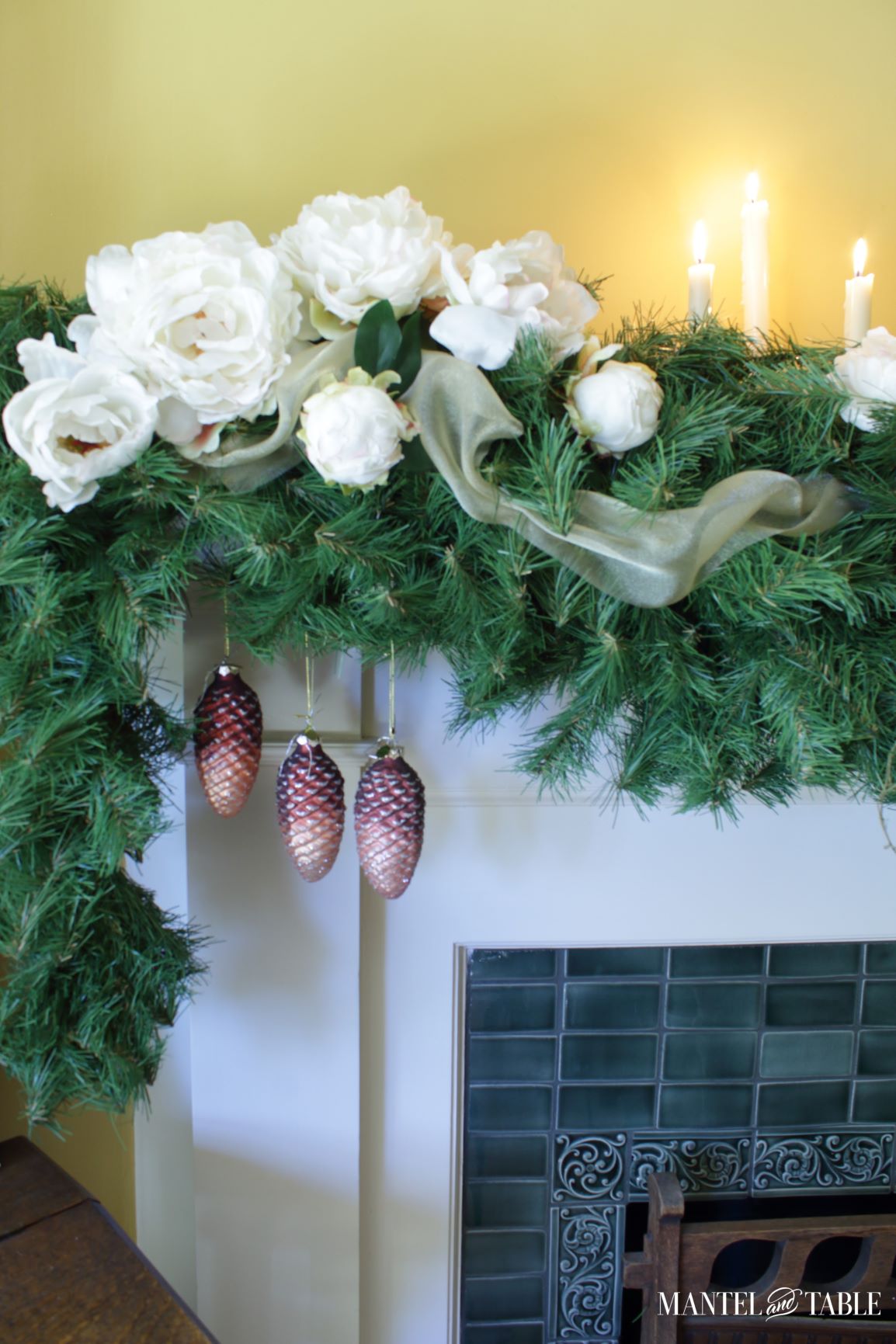 Closeup of blush pinecone ornaments in white peony mantel garland