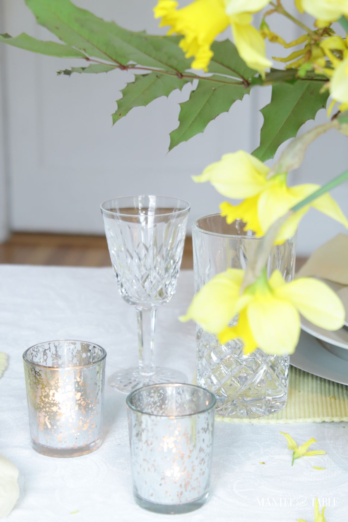Closeup of votive candles, crystal, and daffodils