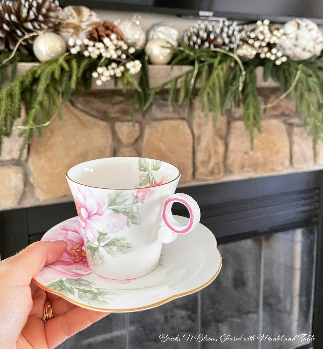 High tea traveling teacup held in front of a mantel decorated for winter