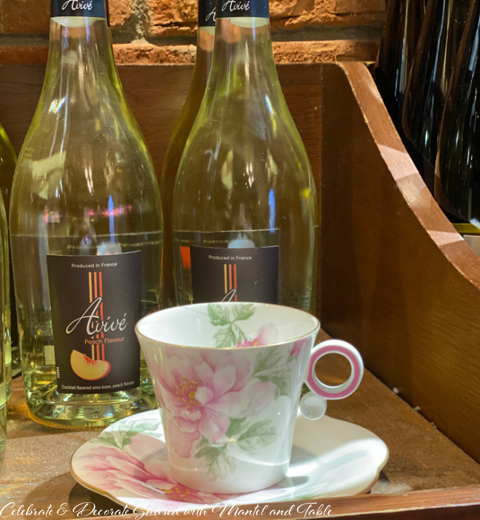 Tea at EPCOT - Pink and white teacup and saucer with bottles of French wine in the background
