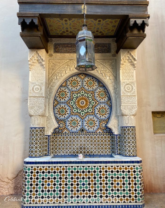 Pink & white teacup sitting on front edge of very large mosaic tile fountain