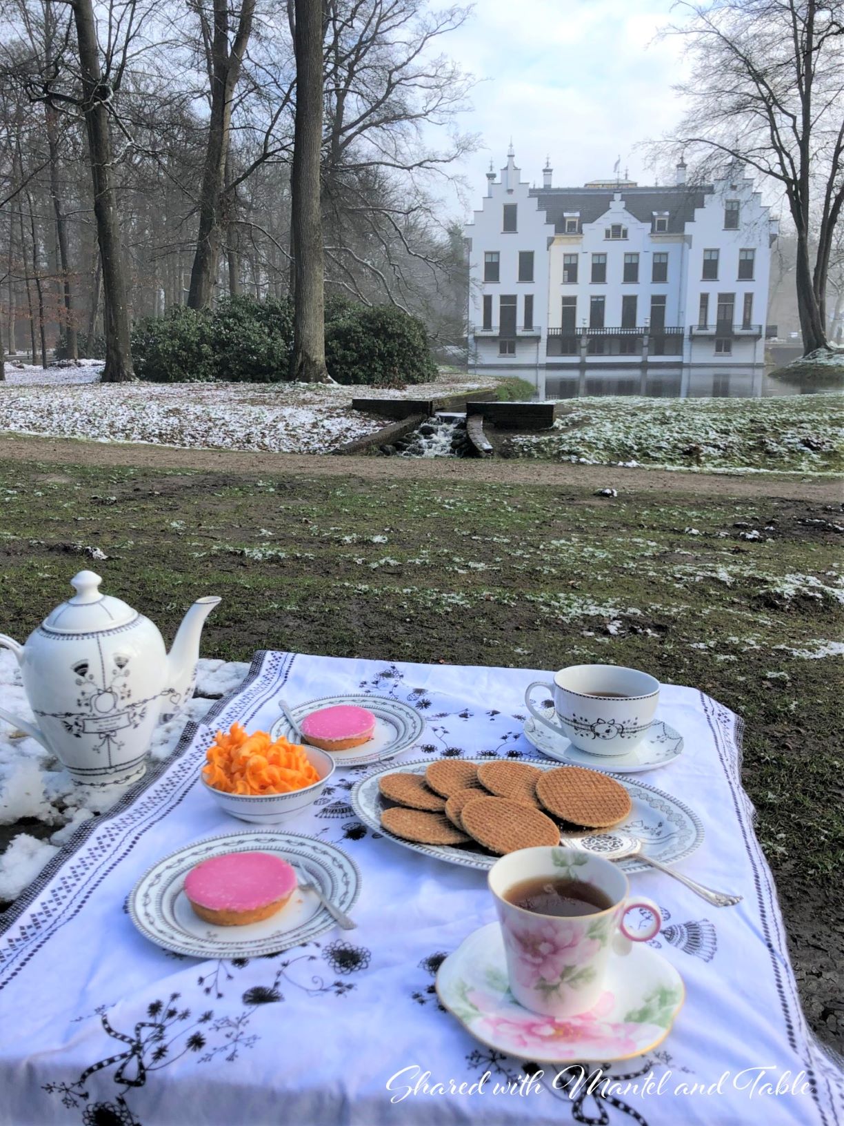 Tea in the Netherlands -light snow on castle and lake with tea table in foreground
