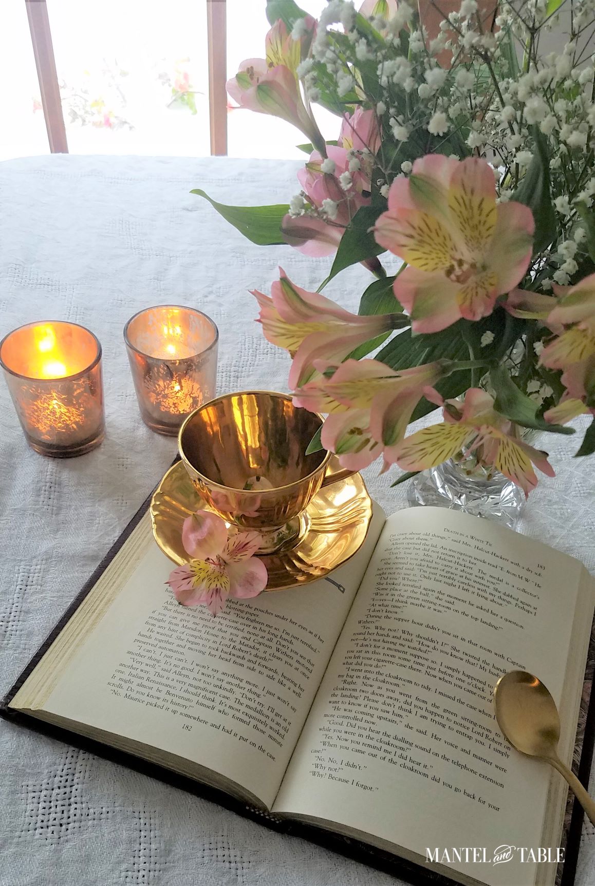 cup and saucer on open book on white tablecloth