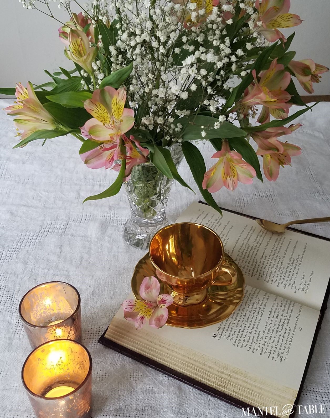 Gold teacup with book, flowers, and candles