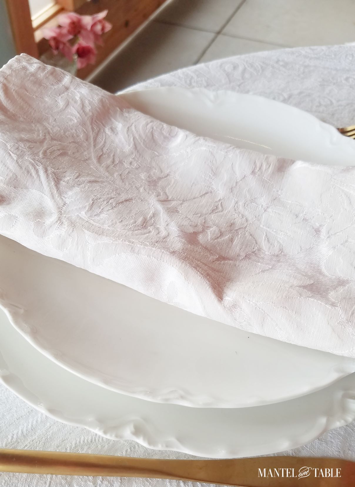 Close up of white plate stack and blush napkin