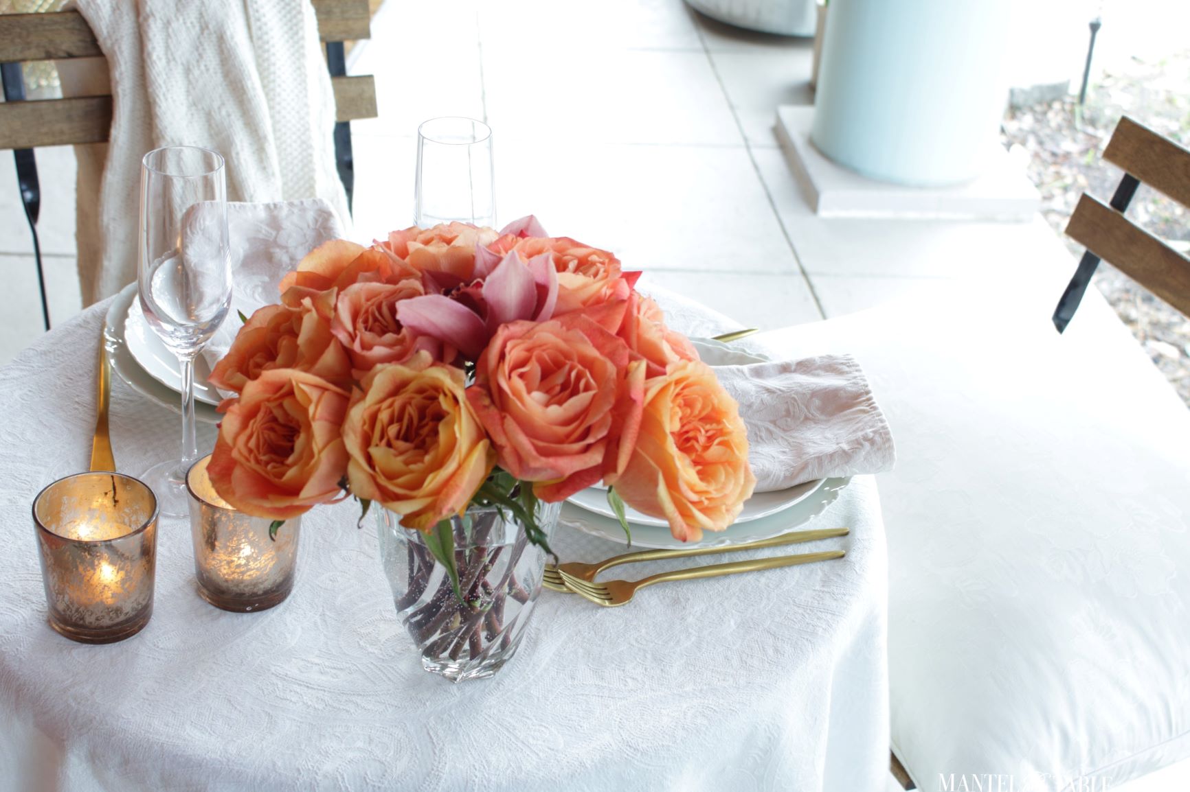 Closeup of table with white tablecloth and peach flower arrangement