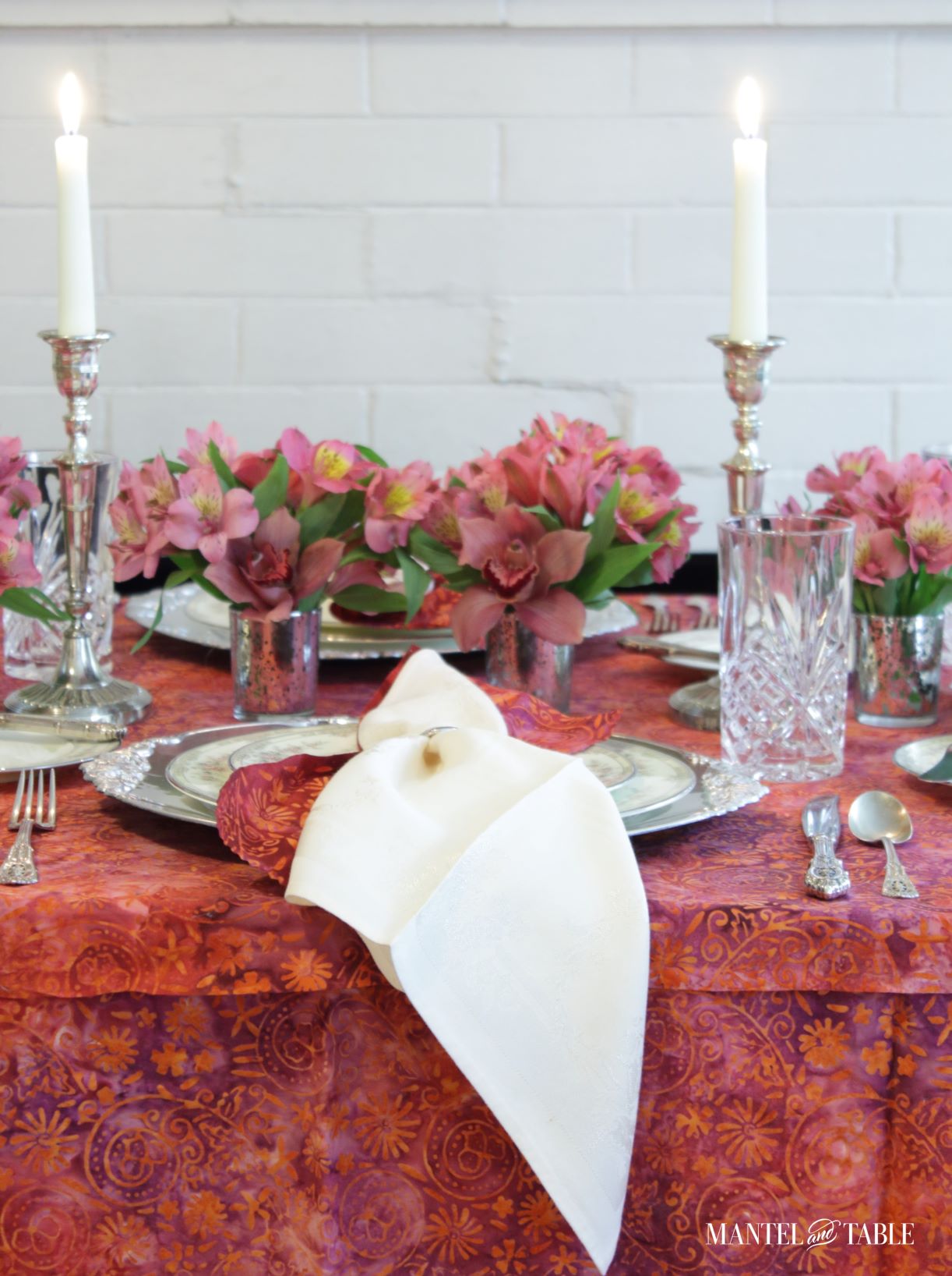 Close up of red, pink, and silver place setting, flowers, and candles