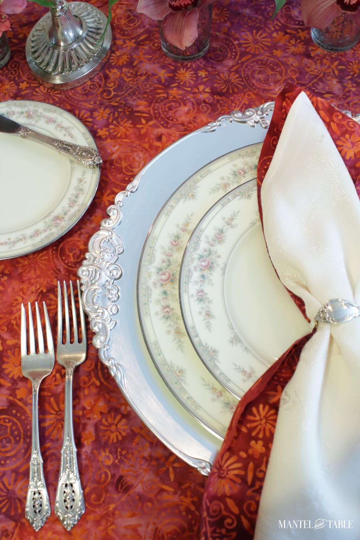Bright Tablescape with closeup of pink and silver plate stack, silver forks, and butter plate in place setting