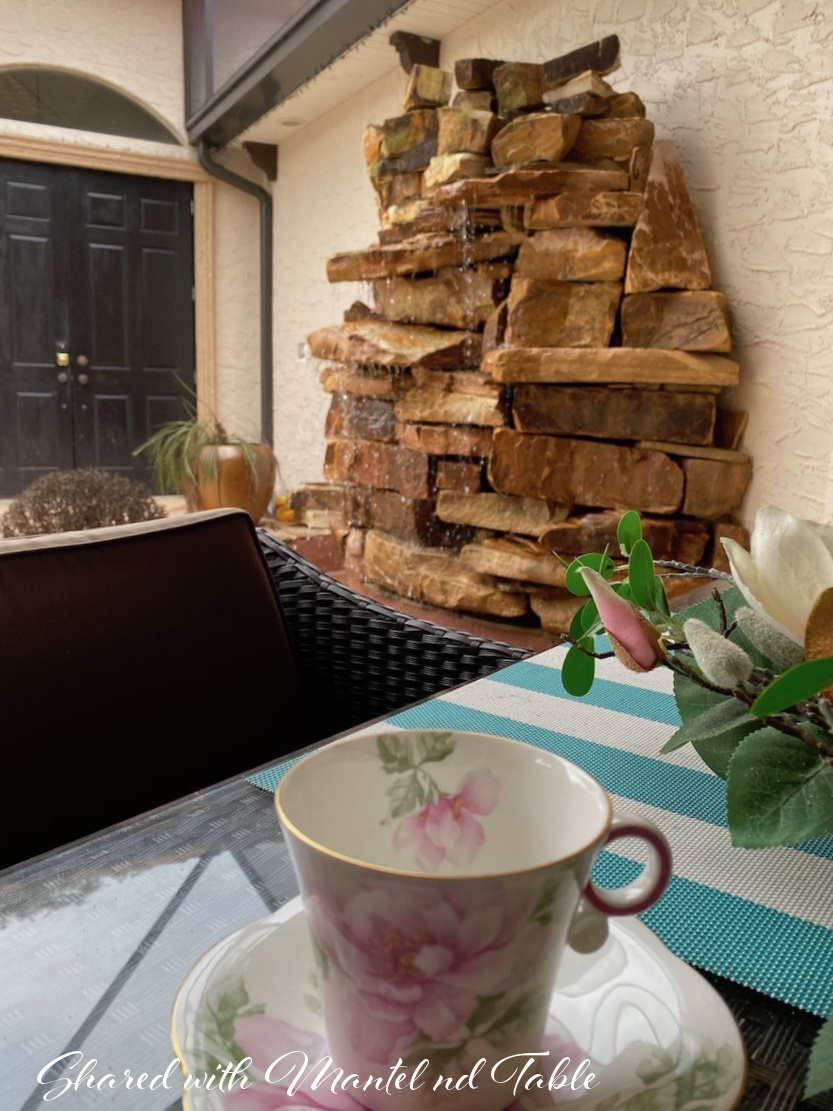 Teacup on a table in front of a lovely rock waterfall