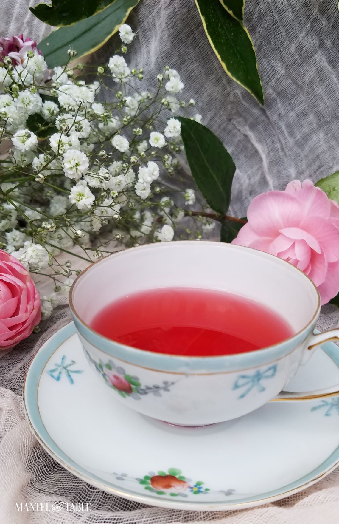 White, baby blue-trimmed, darling teacup filled with deep pink tea