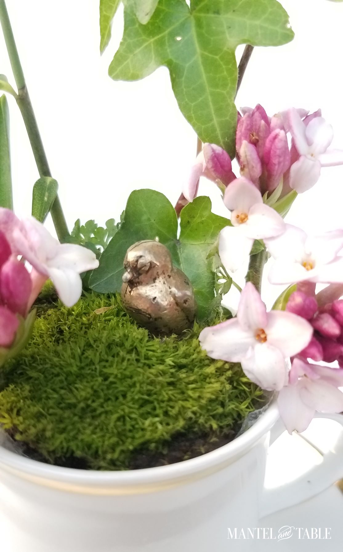 Closeup of tiny brass bird in the teacup garden