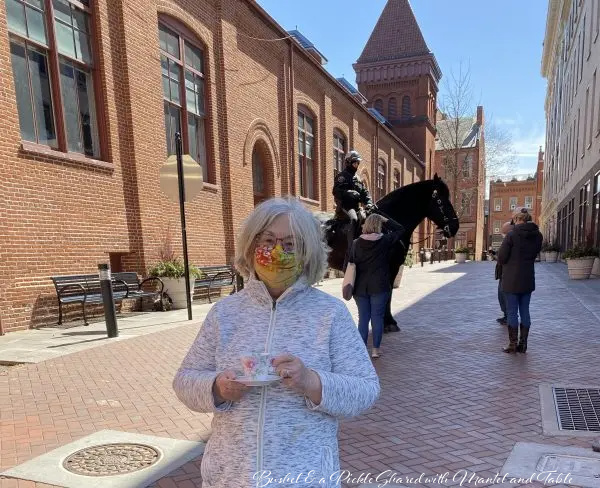 Linda with The Traveling Teacup in brick street with mounted police officer on horse in the background