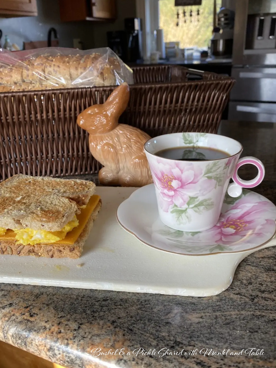 Pink and white flowered teacup on counter with breakfast sandwich