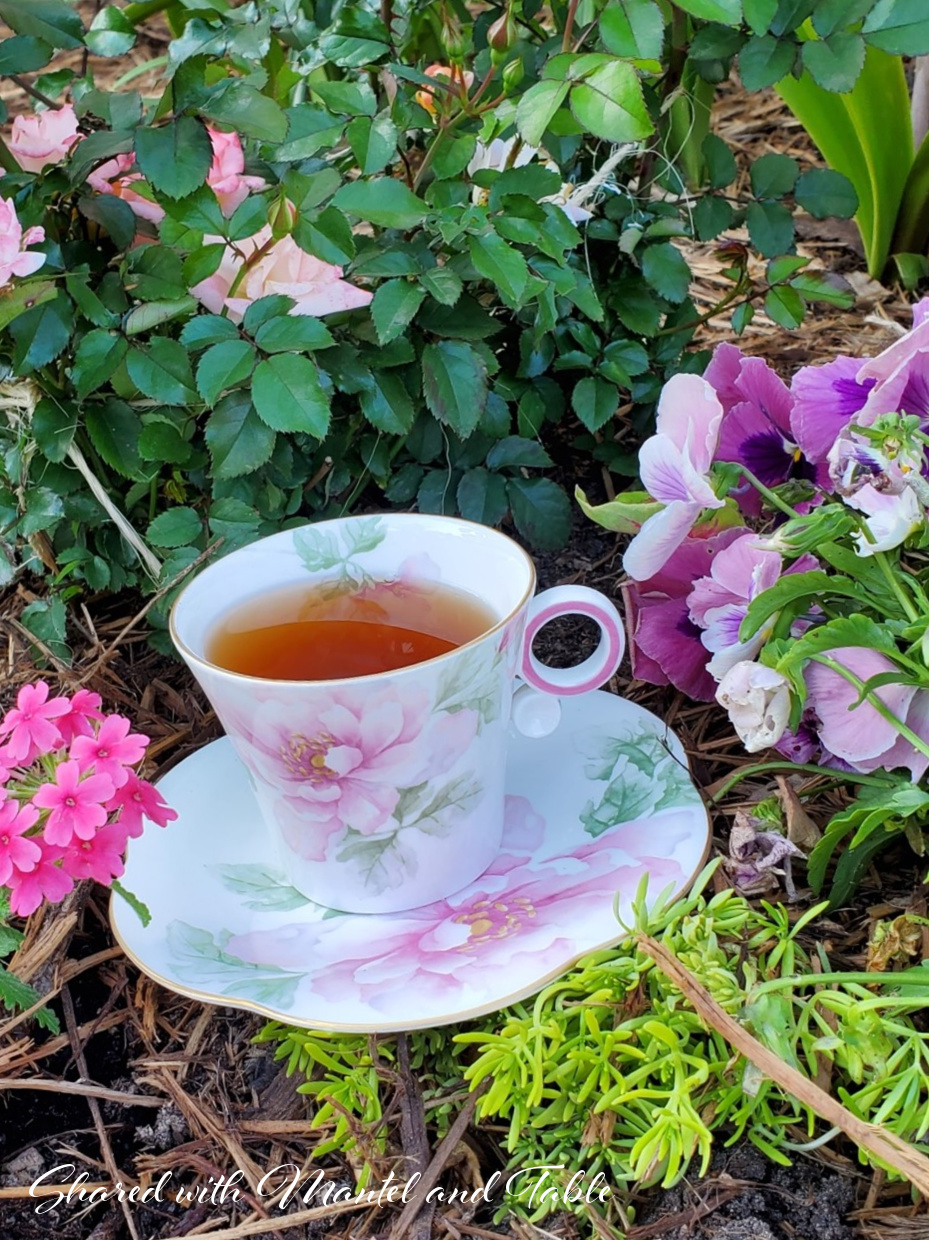Tea in a teacup in a sloping garden with pink and purple flowers