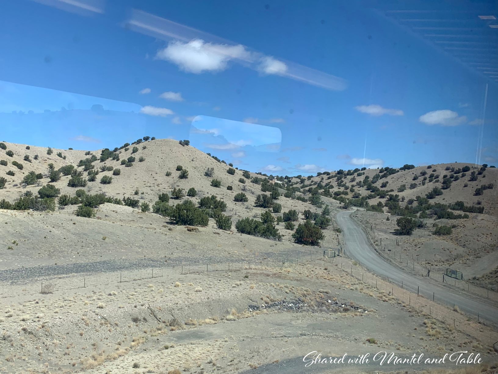 Endless sky, desert, unpaved roads through the train window including reflection of interior