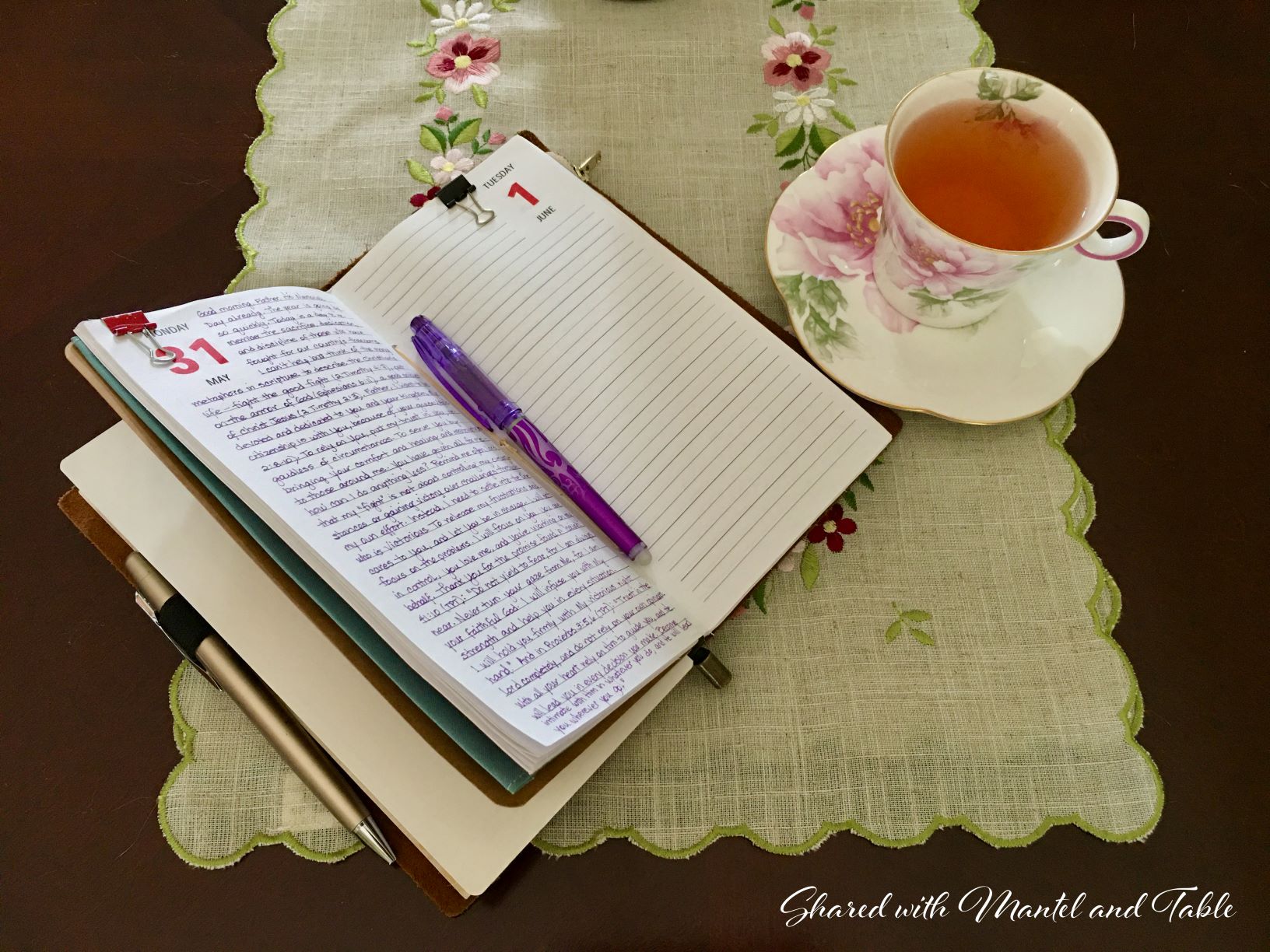 Teacup on table with open journal, pen