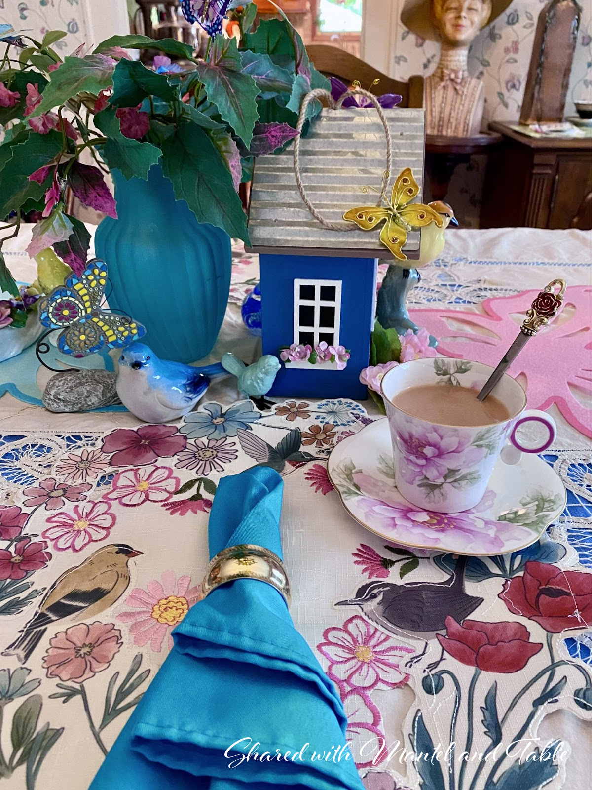 Closeup of blue bird house, birds, butterflies, and flowers centerpiece
