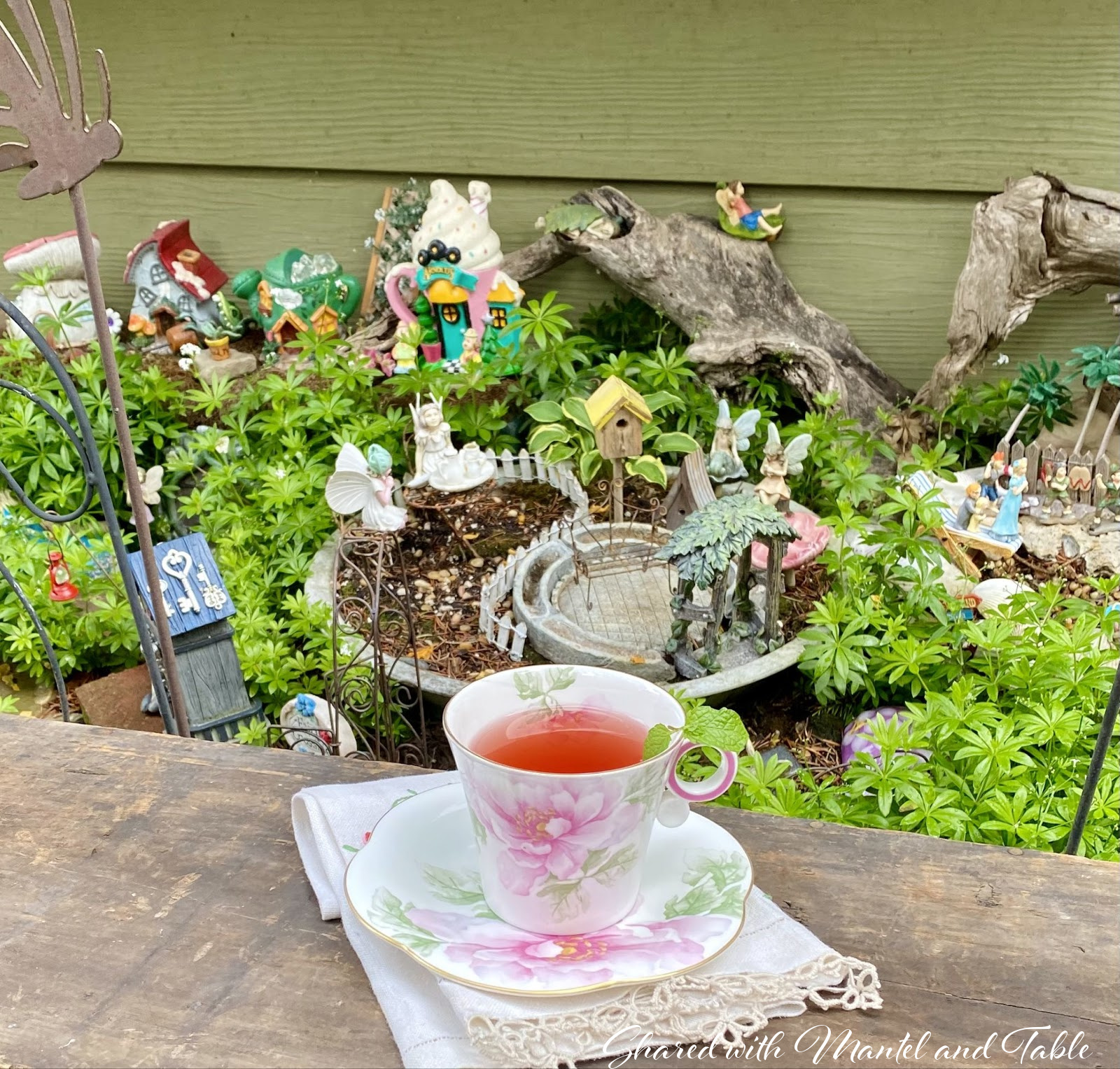 Another section of the fairy garden, cup and saucer in foreground with mint sprig over the rim near the round handle