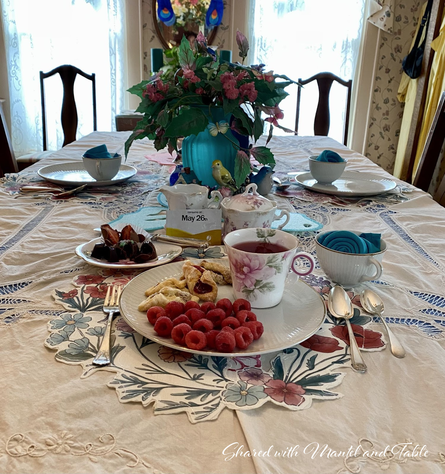 Closeup of place setting, plate with breakfast, cup of tea, chocolate strawberries in the matching saucer