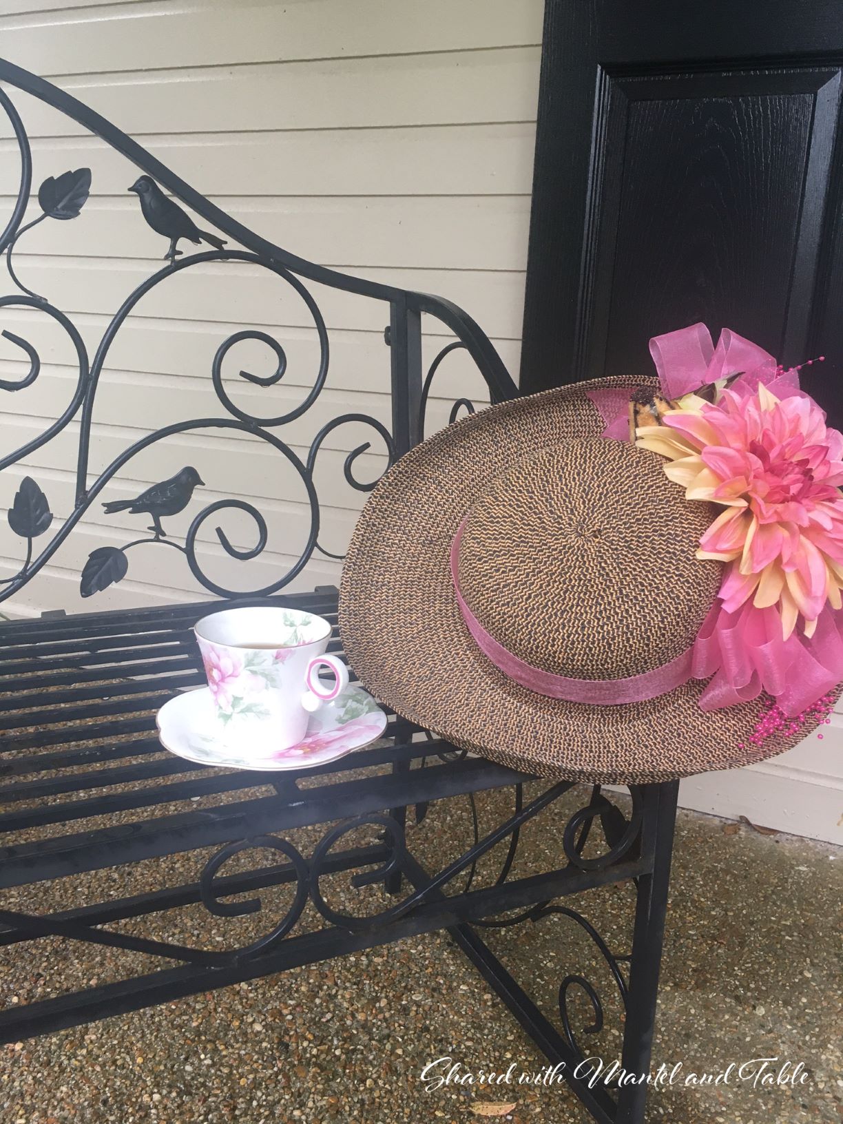 Teacup on black iron bench with pink & yellow flowered straw hat in Louisiana