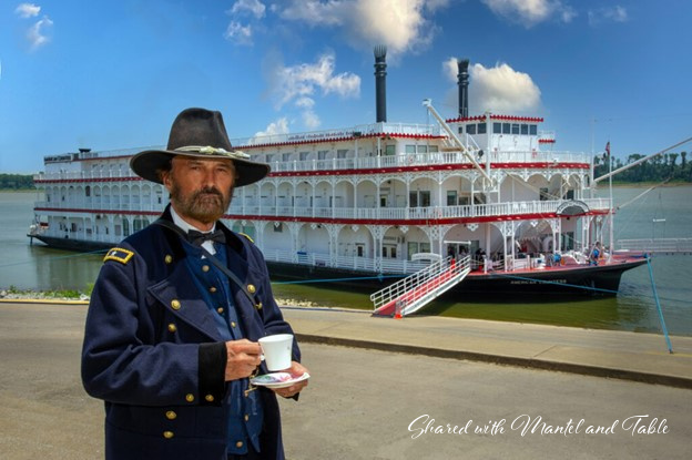 Actor dressed as General Grant holding teacup and saucer in front of steamboat in Paducah KY's harbor
