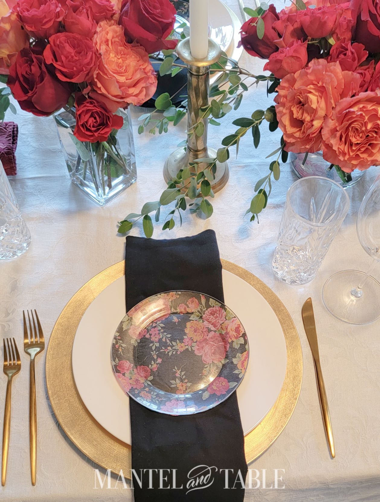 gold and white place setting with black linen and floral salad plate