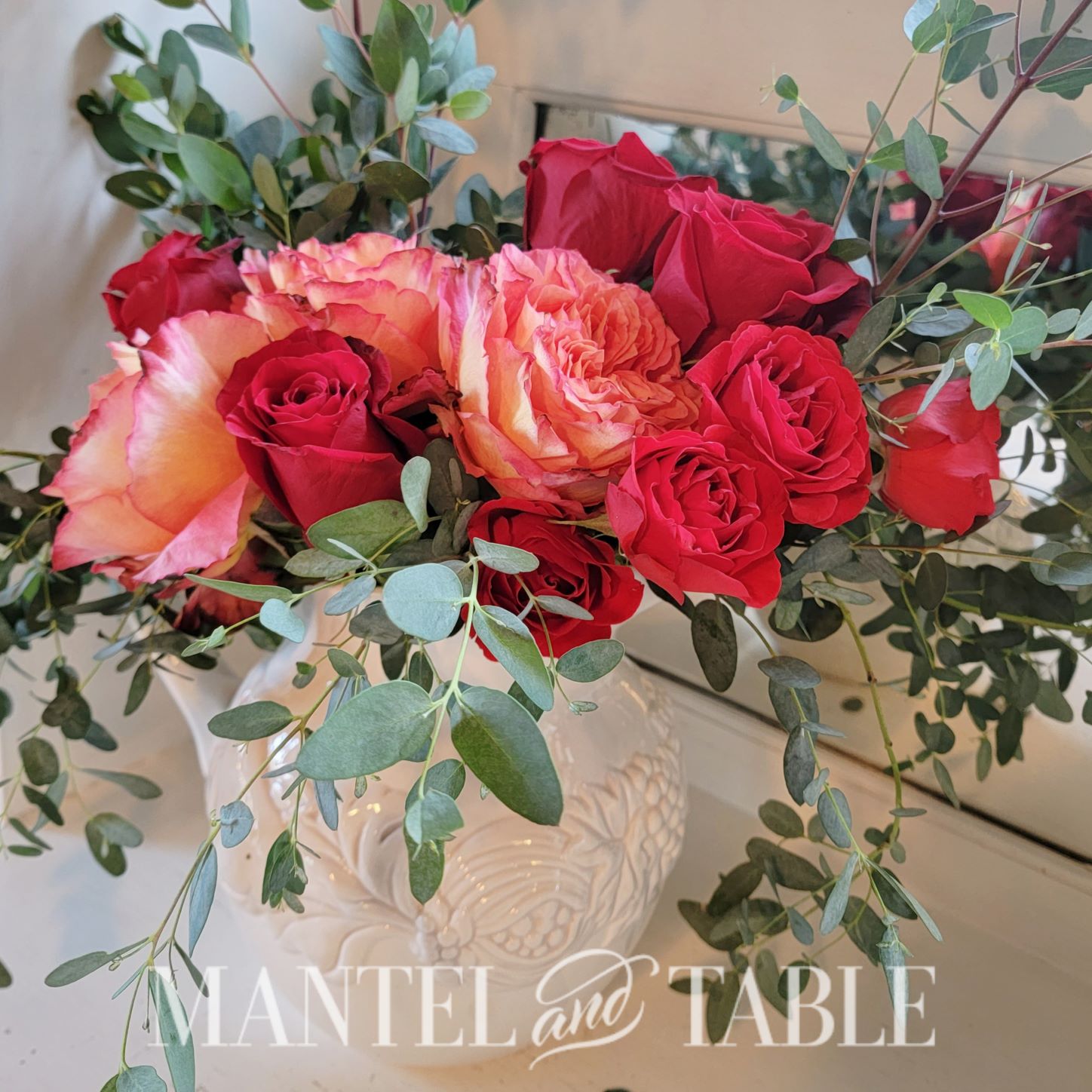 Flower arrangement of red and peach roses with greenery