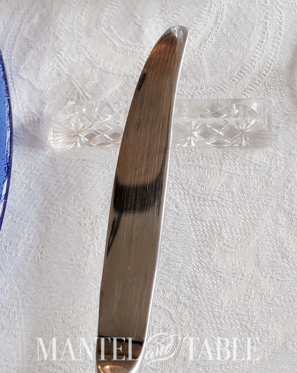 Closeup of table knife blade on crystal knife rest