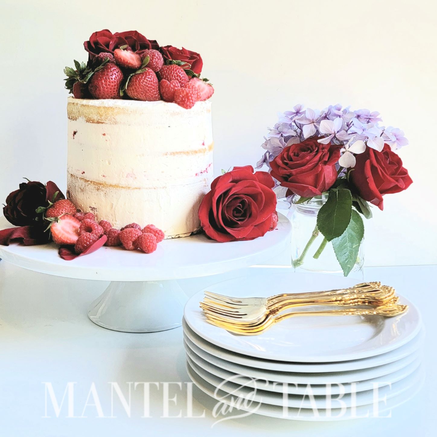 Small champagne cake on stand garnished with berries and roses