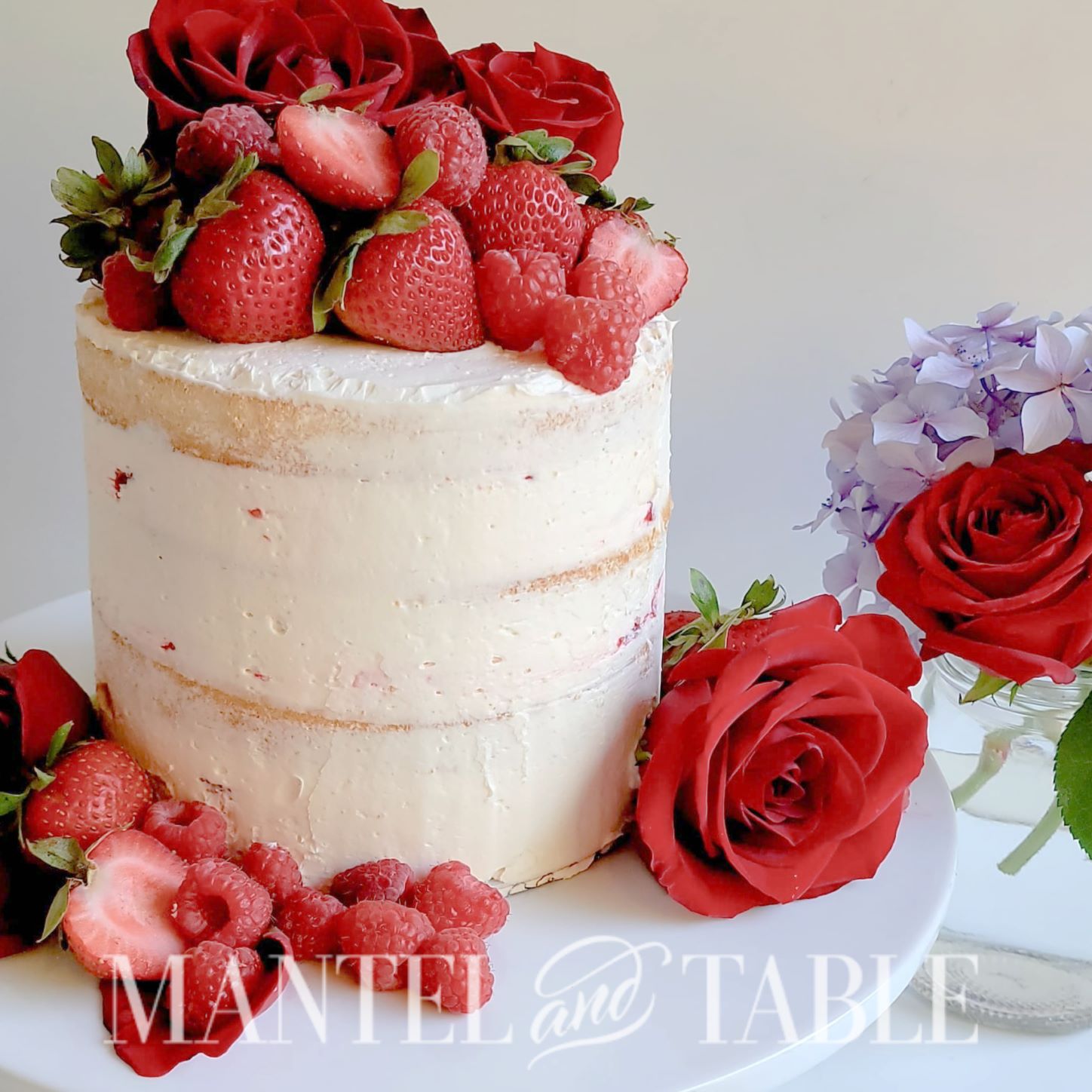 White naked cake with berries and roses