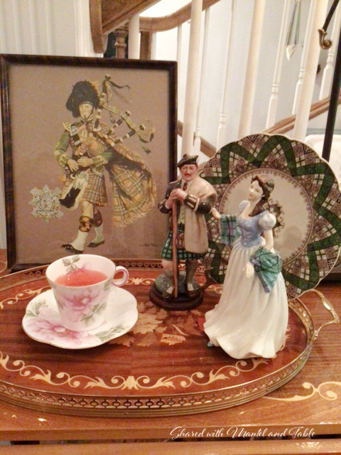 Teacup full of Tiffin, on inlaid wooden tray with Scottish figurines and framed bagpaper art
