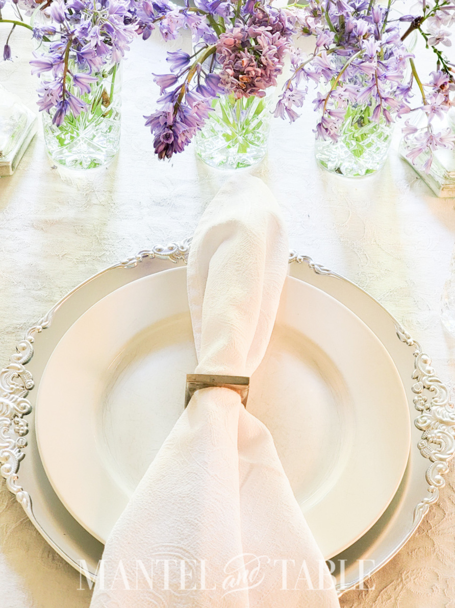 Spring tablescape - white napkin in silver square napkin ring on plate
