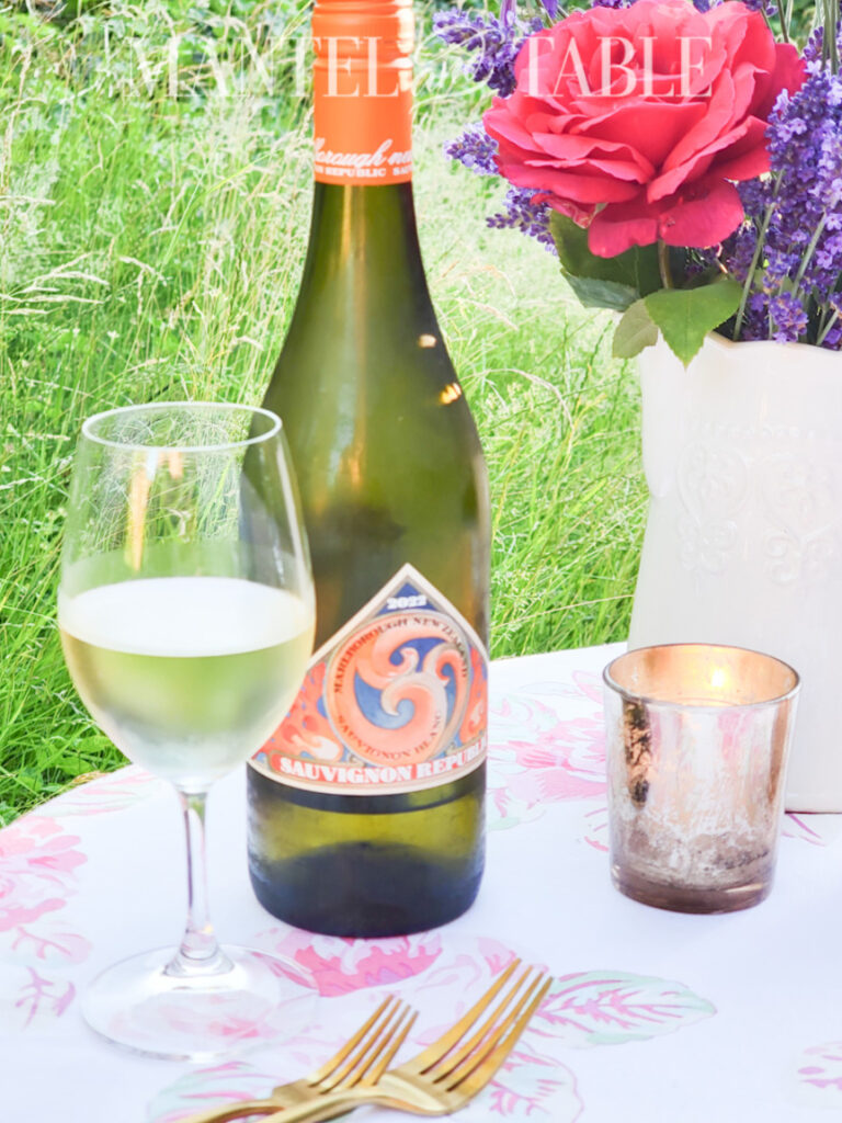 lavender bouquet in vase on table next to bottle of wine and wine in a glass