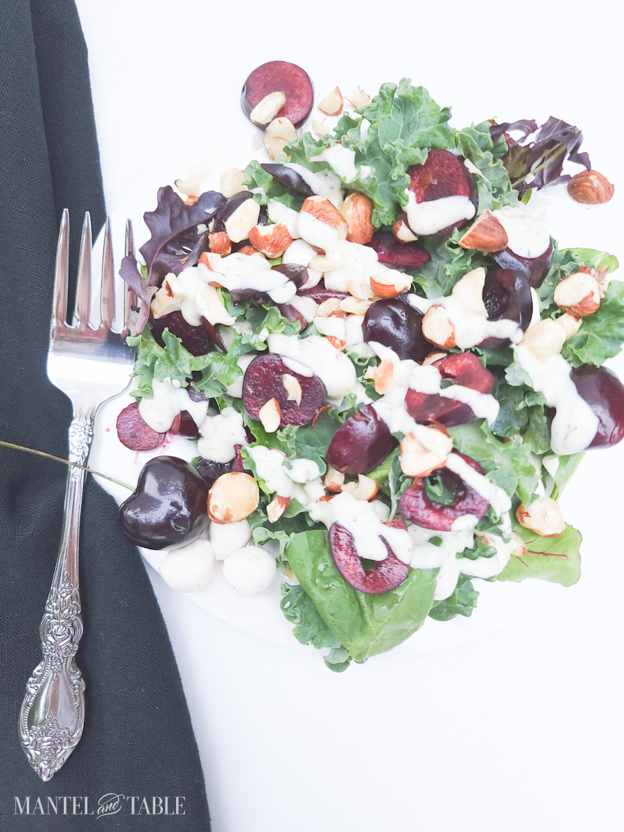 Summer Salad with cherries on white plate, black napkin