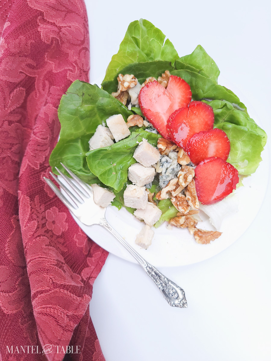 Summer Salad with strawberries and chicken on white plate, red napkin