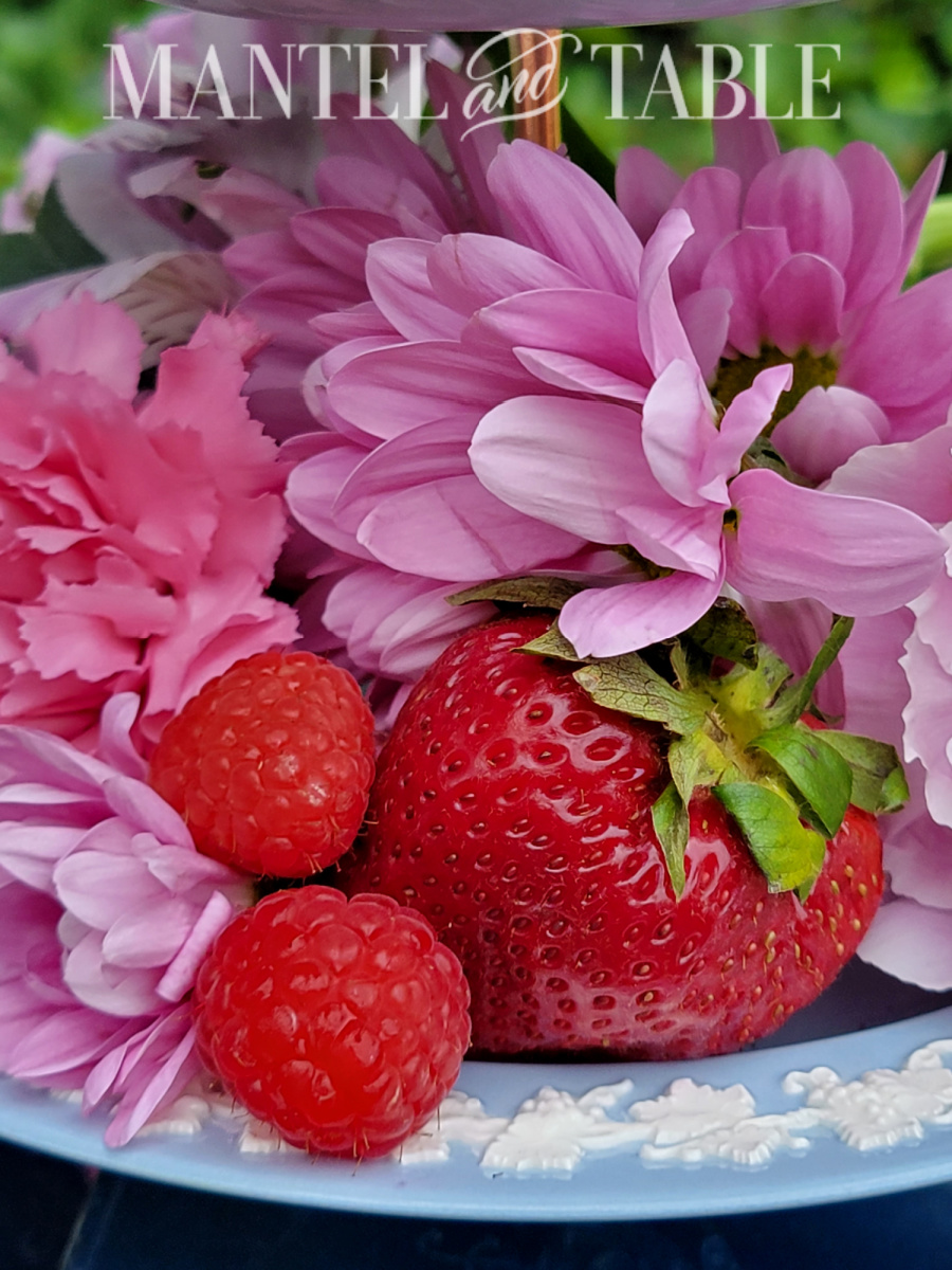 Closeup of strawberry, raspberries, and purple flowers on a blue tray