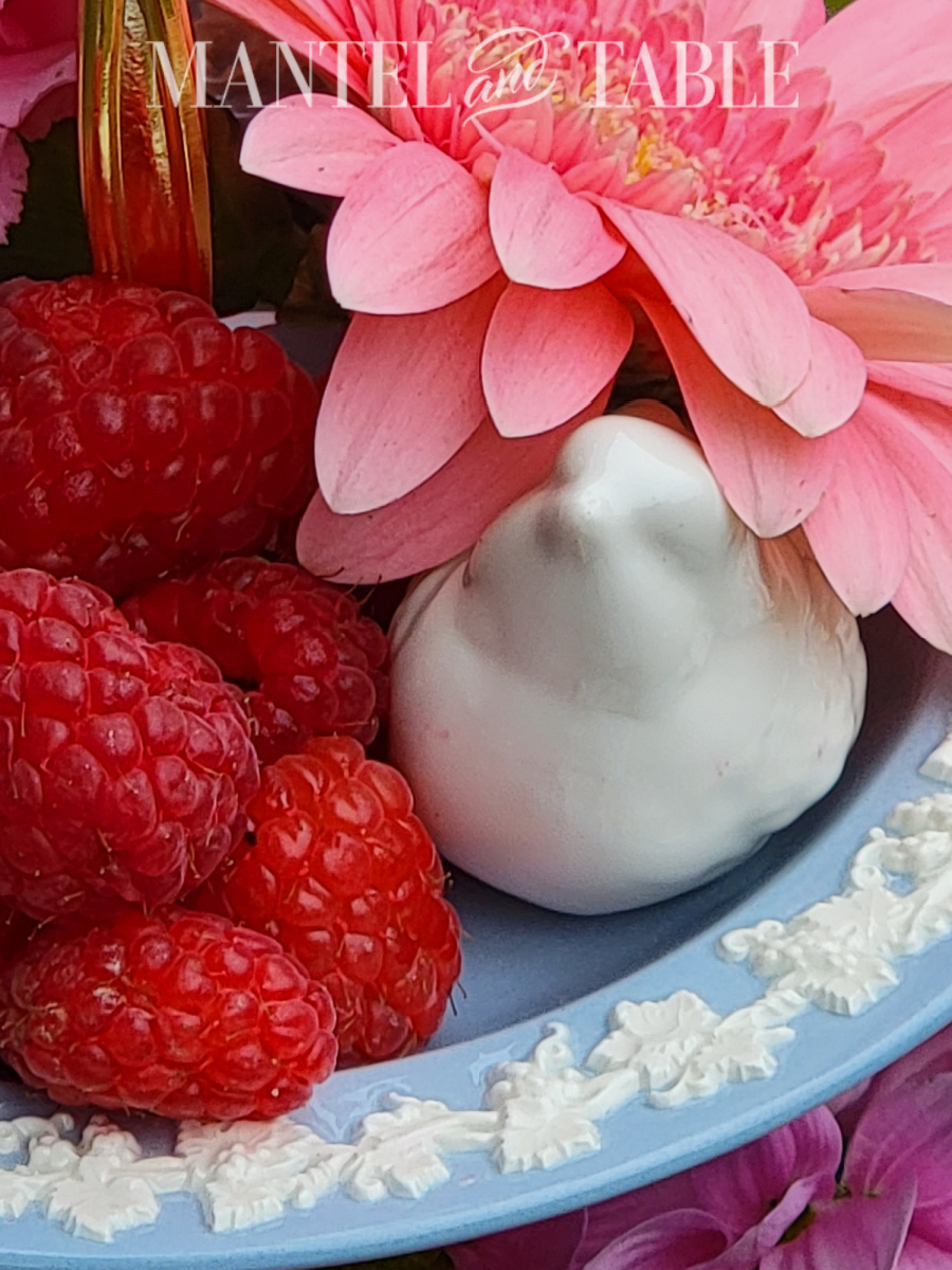 Summer tray decor - closeup of white ceramic bird, pink flower, raspberries
