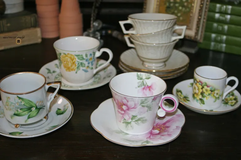 Teacup vignette with four flowered teacups and stack of three white and gold ones