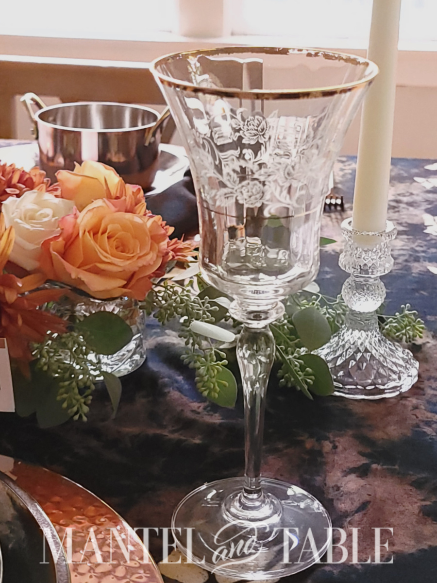 Closeup view of etched wine goblet with gold rim at table setting