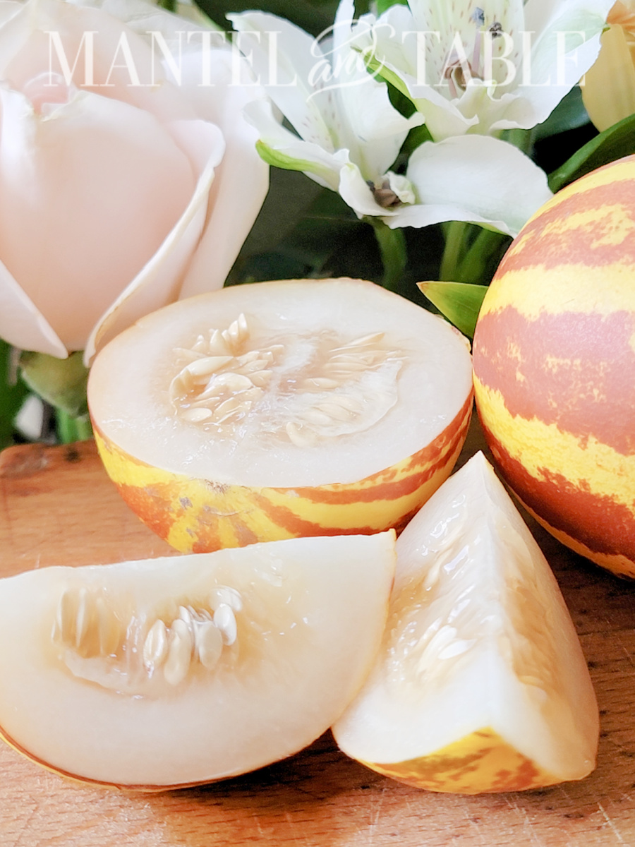 Whole and cut tiger melon with flowers on cutting board