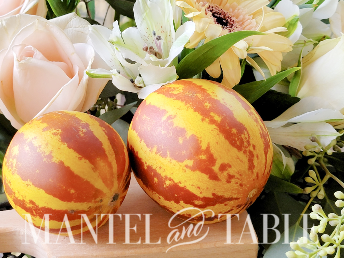 Two whole tiger melons for tiger melon cocktails on cutting board with flowers