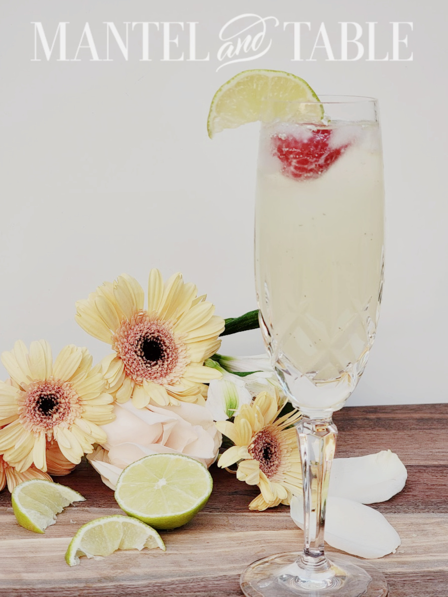 Champagne cocktail in crystal glass with flowers and limes on cutting board