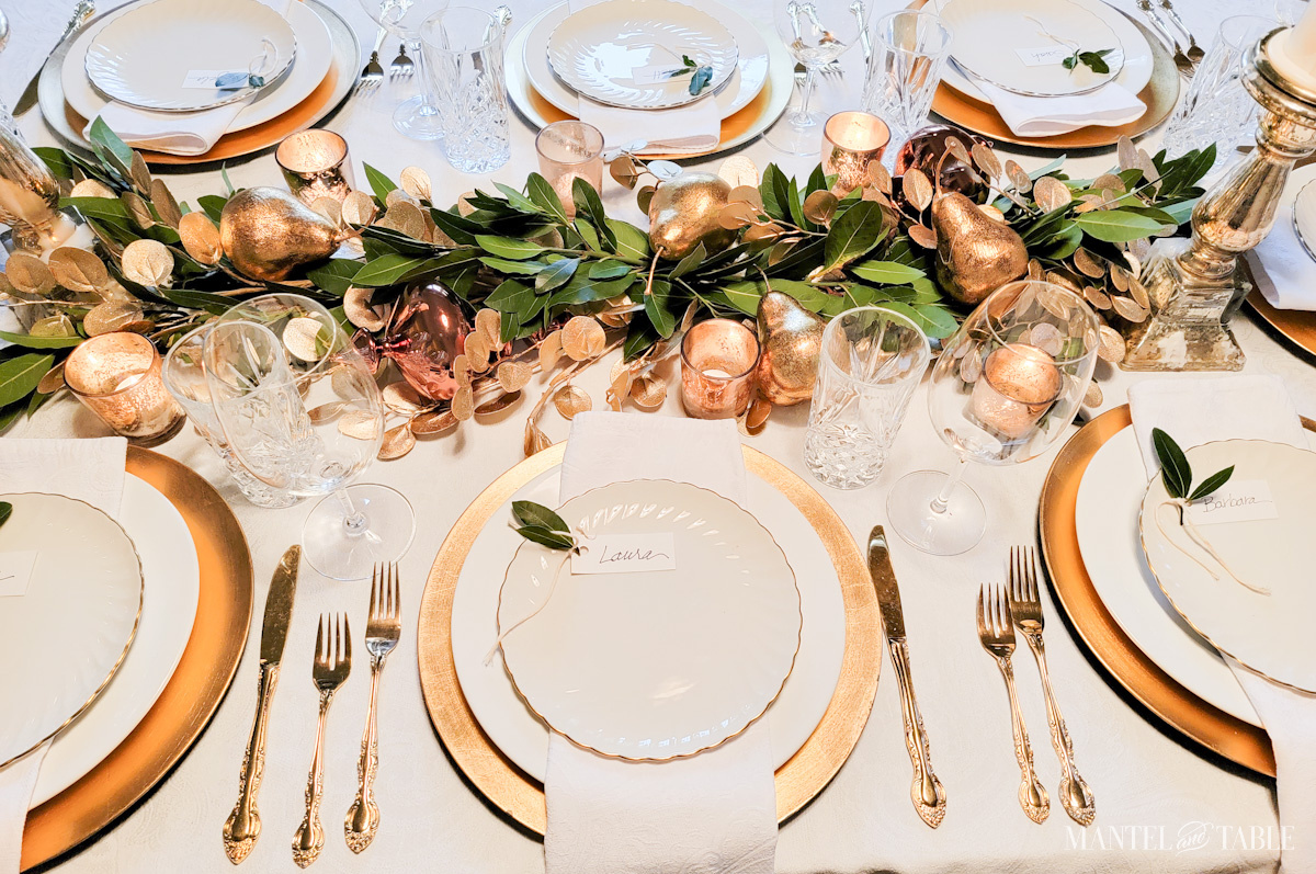 Gold and white table setting with center garland of bay leaves