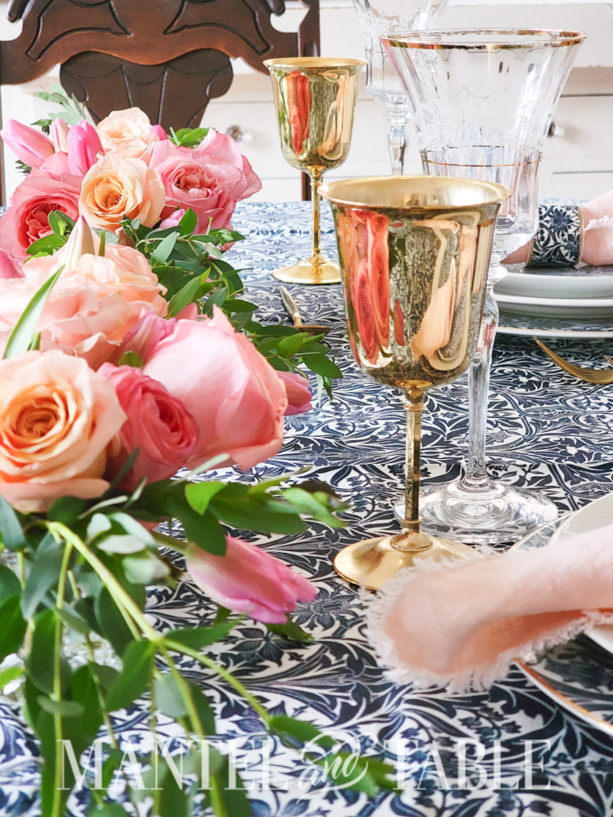 Blue tablescape with pink flowers and gold goblets