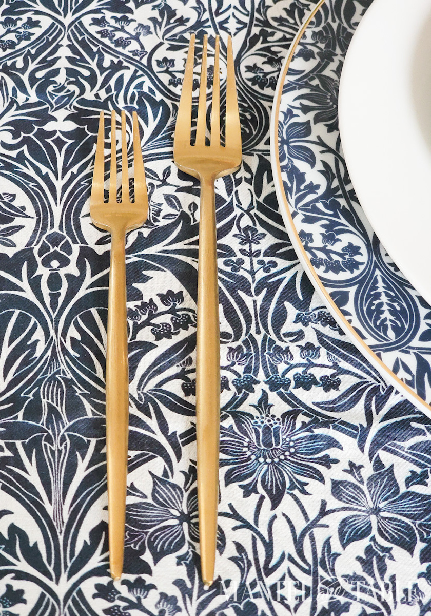 Closeup of gold forks set on a blue tablescape