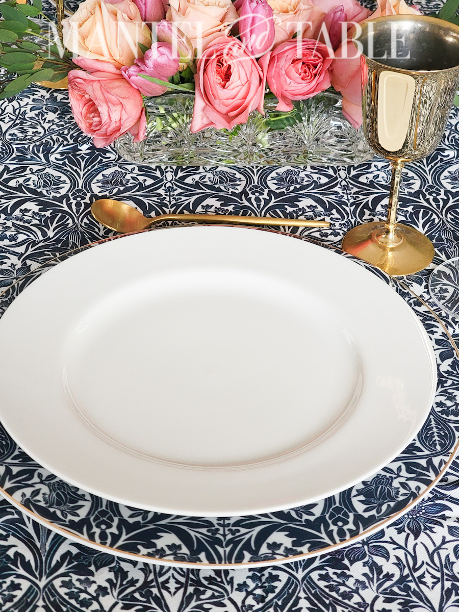 White dinner plate on blue patterned charger and tablecloth